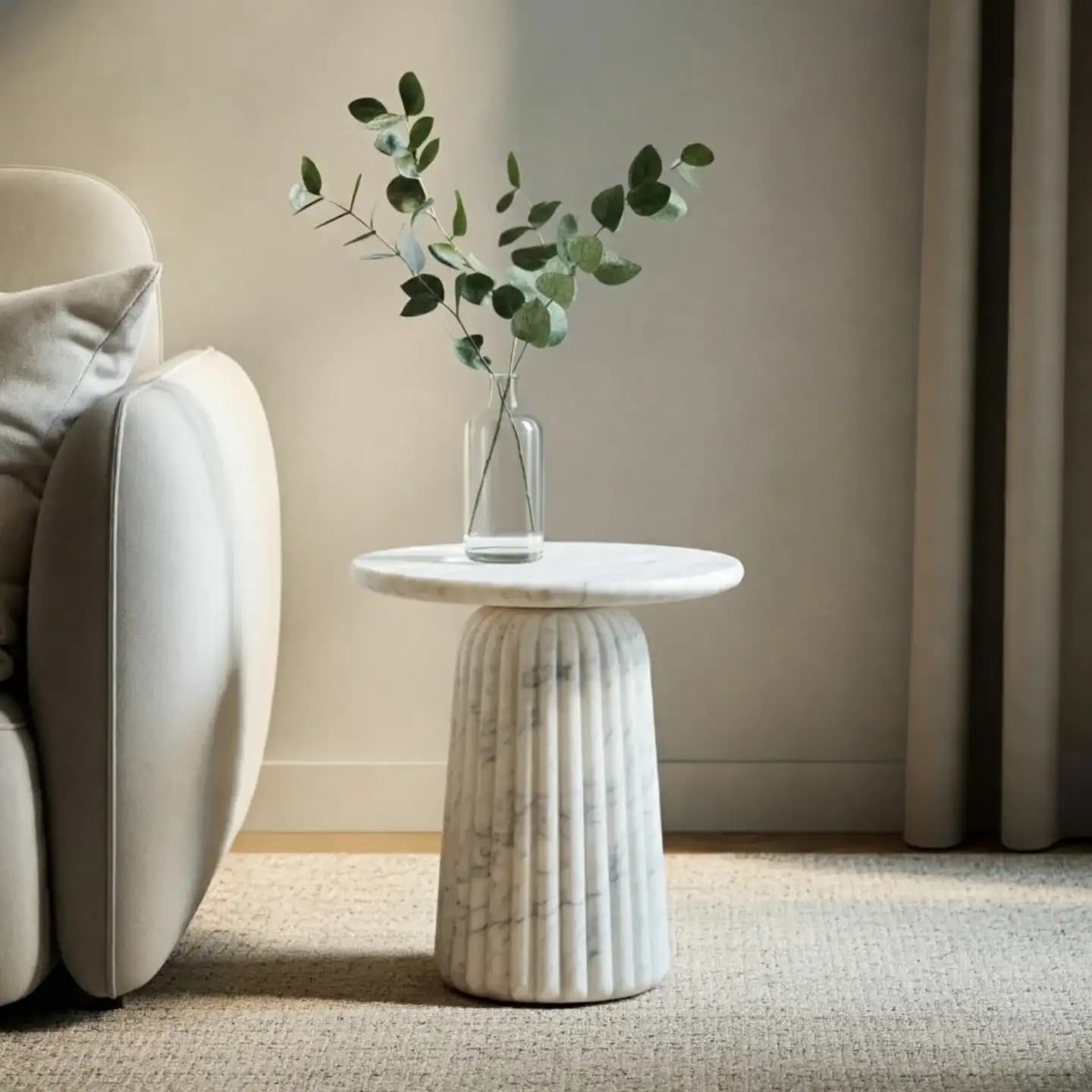 A small round side table in white marble with a fluted pedestal base
